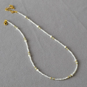 Detail of beaded necklace with turquoise and shell beads featuring gold lobster clasp closure