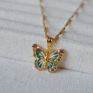 Détail d'un pendentif papillon doré avec émail bleu et zircons colorés étincelants