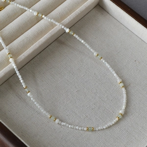Minimalist beaded necklace with turquoise and white stones on a jewelry display tray