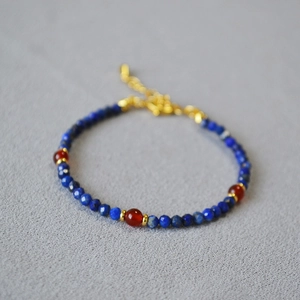 Macro shot of lapis lazuli beads with red agate accents and golden lobster clasp detail