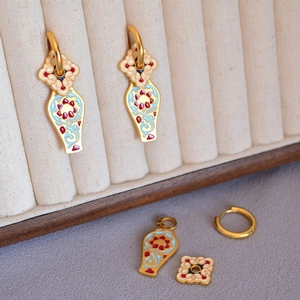Détail macro de boucles d'oreilles en émail chinois avec éléments amovibles en laiton