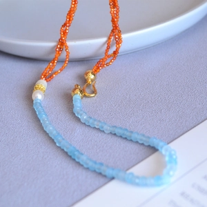 Detail of beaded necklace with blue faceted stones, pearls and golden metal clasp