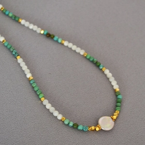 Close-up of turquoise beads with white pearls and a baroque pearl pendant on the necklace