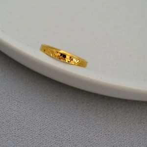 Minimalist gold-plated dragon scale ring with hammered texture on white ceramic dish