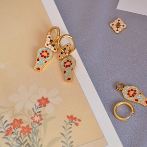 Détail de boucles d'oreilles en émail plaqué or avec pendentifs amovibles en fleurs