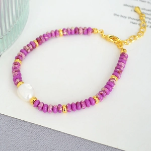 Macro shot of purple beaded bracelet with baroque pearl and golden lobster clasp closure