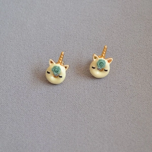 Detailed view of handmade enamel unicorn donut stud earrings with a blue rose detail