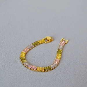 Detailed close-up of brass gold plated bracelet with gradient rectangular colored zircons