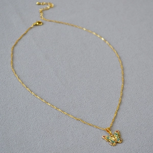 Détail du pendentif papillon en émail et zircons colorés sur une fine chaîne dorée