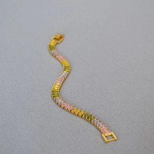 Detail of gold plated buckle bracelet featuring a gradient of multi-colored zircon stones