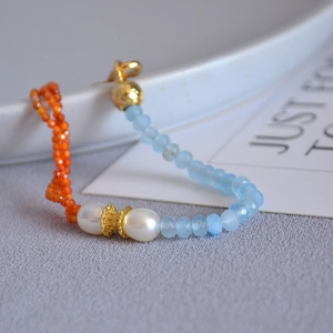 Detail of beaded necklace with blue faceted stones, pearls, and gold-tone spacers