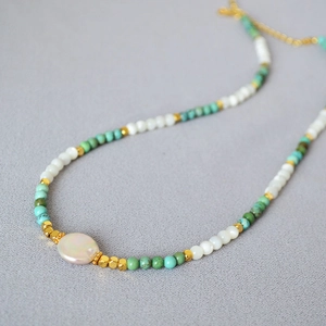 Bohemian style necklace with turquoise beads, white shells, and a large freshwater pearl