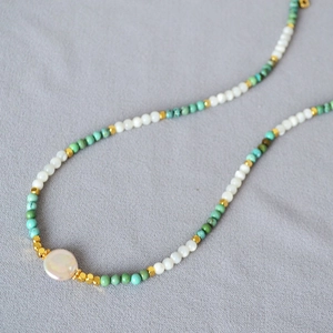 Detail of beaded necklace with turquoise beads, white pearls and pink baroque pearl pendant