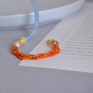 Macro detail of blue gemstone beads and freshwater pearls with gold floral spacers