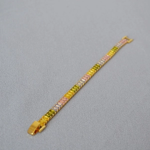 Detailed macro view of colorful baguette-cut zircons and gold buckle on a wide band bracelet