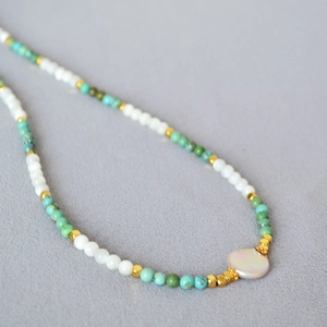 Detail of beaded necklace with turquoise beads, freshwater pearls and golden spacers