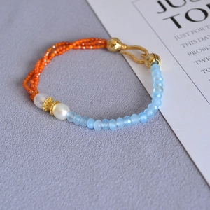 Detail of beaded necklace with blue faceted stones, orange beads and white pearls