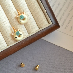 Macro view of handmade enamel unicorn donut stud earrings with rose detail on tray