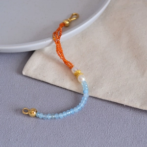 Detail of freshwater pearl necklace with faceted sea blue beads and orange accents
