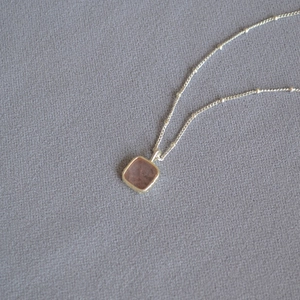 Detailed close-up of a square light blue gemstone pendant with silver-plated handmade edging