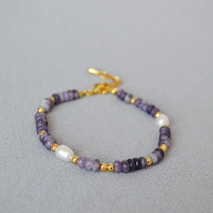 Macro detail of lilac beads, freshwater pearls and gold clasp on minimalist bracelet