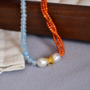 Macro detail of sky blue faceted beads and orange chain with freshwater pearl accents