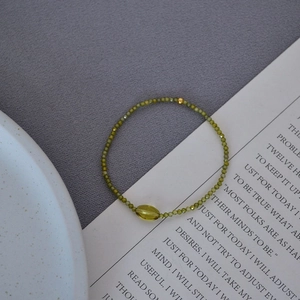 Detail of faceted olive green beads with a central marquise stone on a stretch bracelet