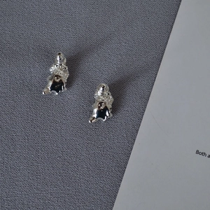 Irregular lava texture silver earrings with organic liquid metal design on grey fabric
