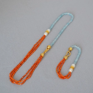 Detail of beaded necklace with blue gemstones, orange beads and white pearls