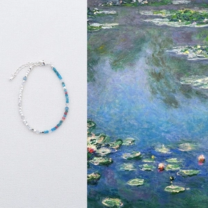 Detail of beaded necklace with silver, blue, and pink stones next to Monet art background