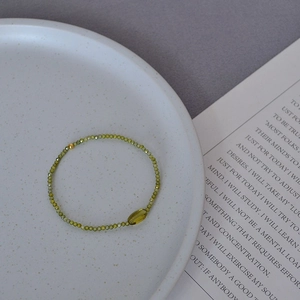 Macro shot of olive green beaded stretch bracelet with faceted stones and a gold bead