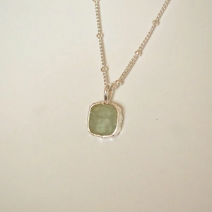 Macro view of handmade bezel square sea blue pendant on silver satellite chain necklace