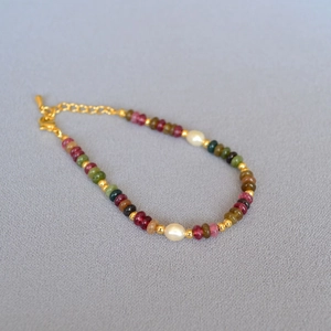 Macro detail of multi-color gemstone beads and white pearls with golden lobster clasp