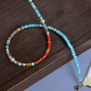 Detail of colorful amazonite beaded necklace with golden lobster clasp on rustic wood