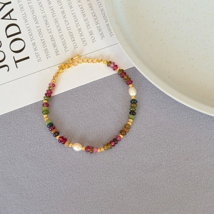 Detailed macro view of colorful gemstone beads and freshwater pearls on a delicate gold chain