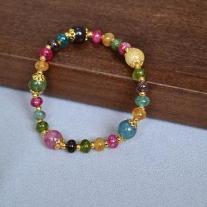 Detail of handmade beaded bracelet with colorful tourmaline stones and gold accents