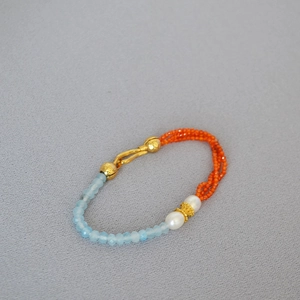 Detail of beaded bracelet with blue faceted stones, red beads, and white pearls