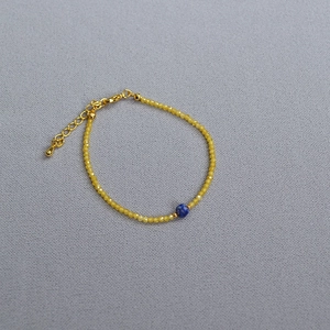 Detailed view of yellow faceted beads and blue lapis bead with adjustable gold clasp
