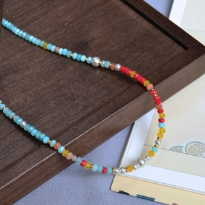 Detail of colorful faceted Amazonite beads with white pearls and gold spacers on a tray