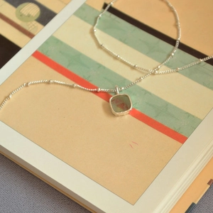 Macro shot of a geometric square aquamarine pendant on a silver bead chain necklace