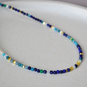 Macro view of Lapis Lazuli crystal beaded necklace with gold spacers on ceramic plate