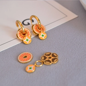 Détail macro de boucles d'oreilles émaillées agrume et fleurs avec pendentifs
