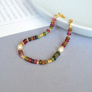 Detailed shot of multi-colored stone bead bracelet with pearls and golden spacers