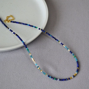 Detailed close-up of colorful faceted beaded necklace with golden cube spacer accents
