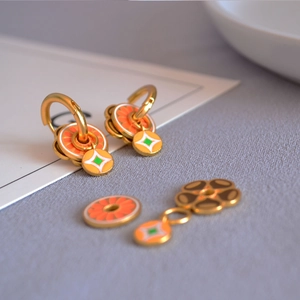 Détail de boucles d'oreilles en laiton doré avec breloques en émail faites main