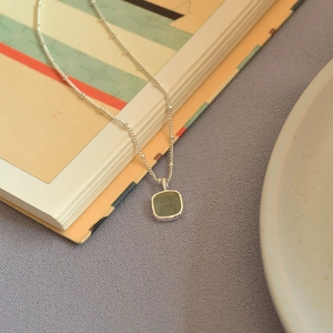 Detailed macro of a green gemstone pendant with handmade silver bezel on satellite chain