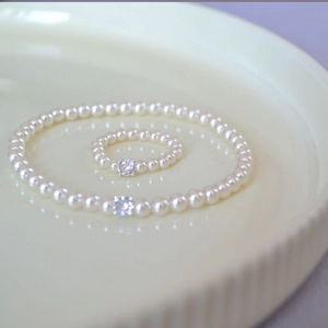 Detailed view of elegant pearl bracelet and ring set with sparkling zirconia in a ceramic tray