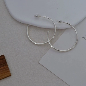 Minimalist silver geometric hoop earrings with polished finish on display