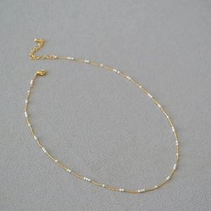 Détail d'un collier en laiton doré avec mini perles et fermoir mousqueton ajustable