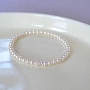 Macro detail of elastic pearl bracelet featuring a central square claw-set zircon stone